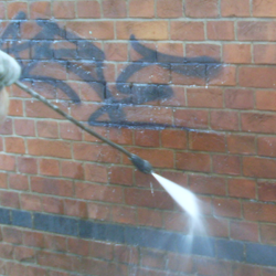 High pressure water jet removing graffiti from a brick wall