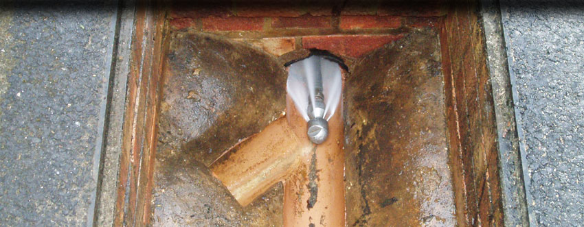 Jetting nozzle clearing a drain inside an open manhole